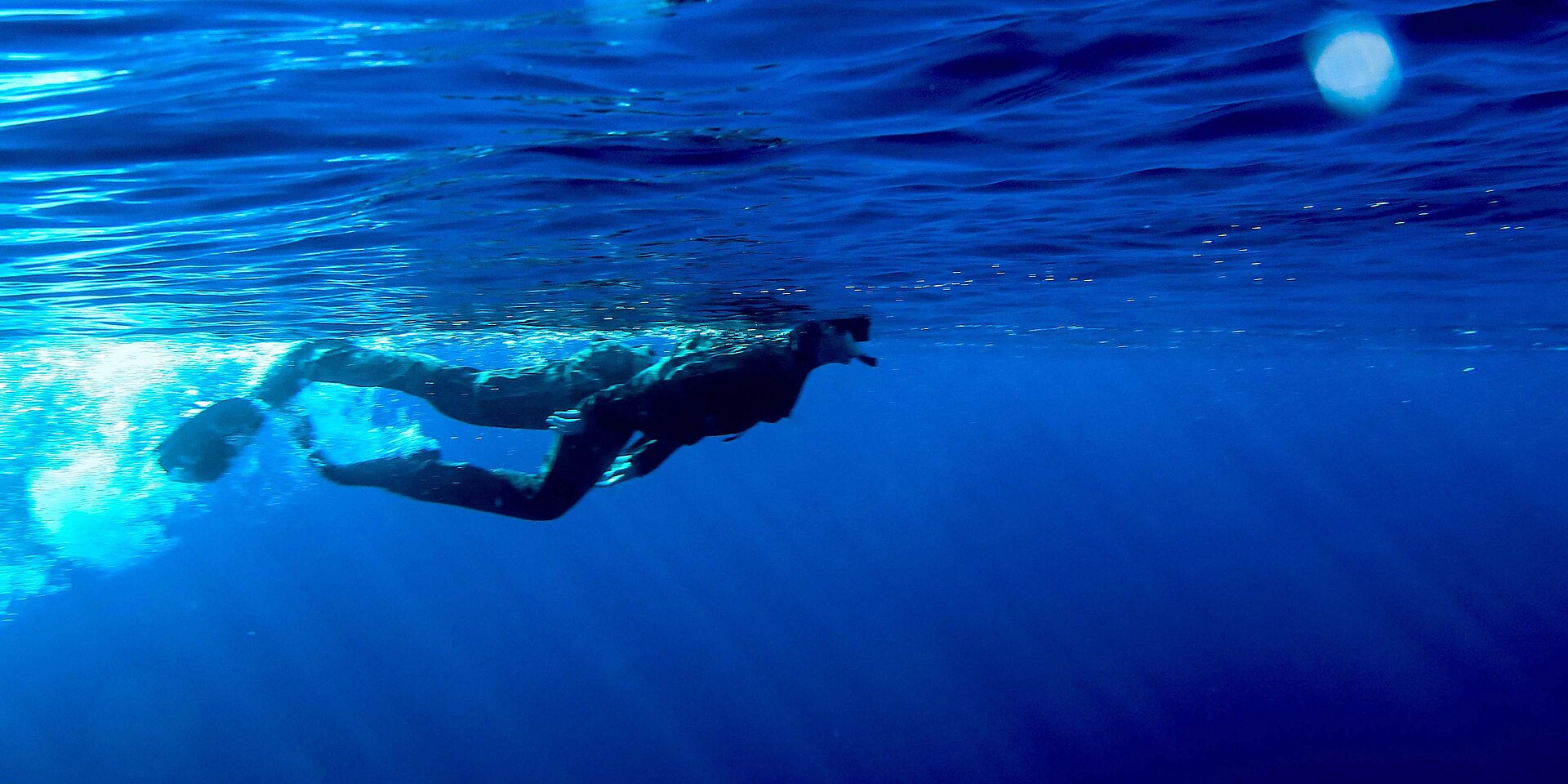 A freediver swimming just below the surface in open water
