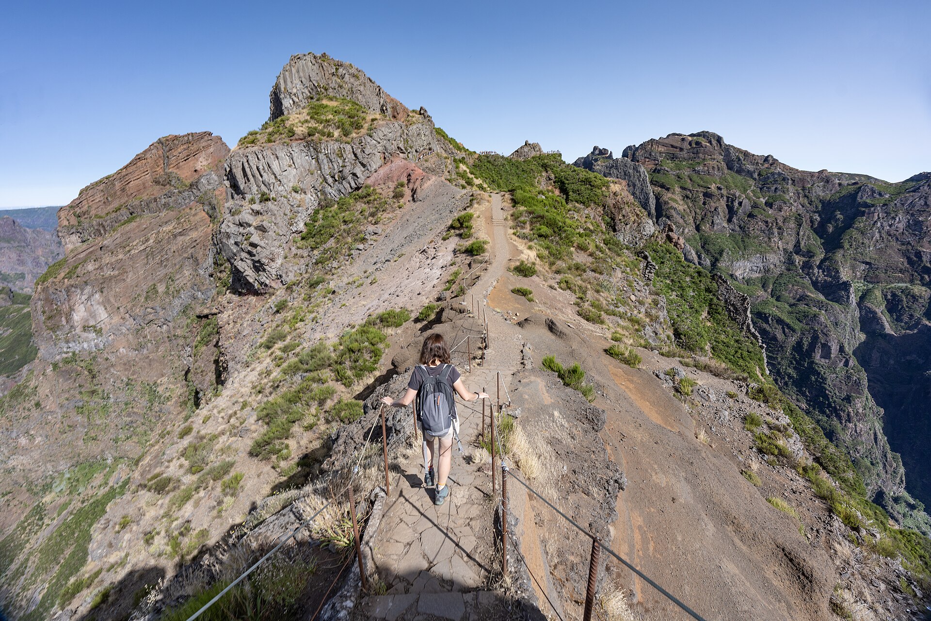 A hiker descending a stony ridgeline trail